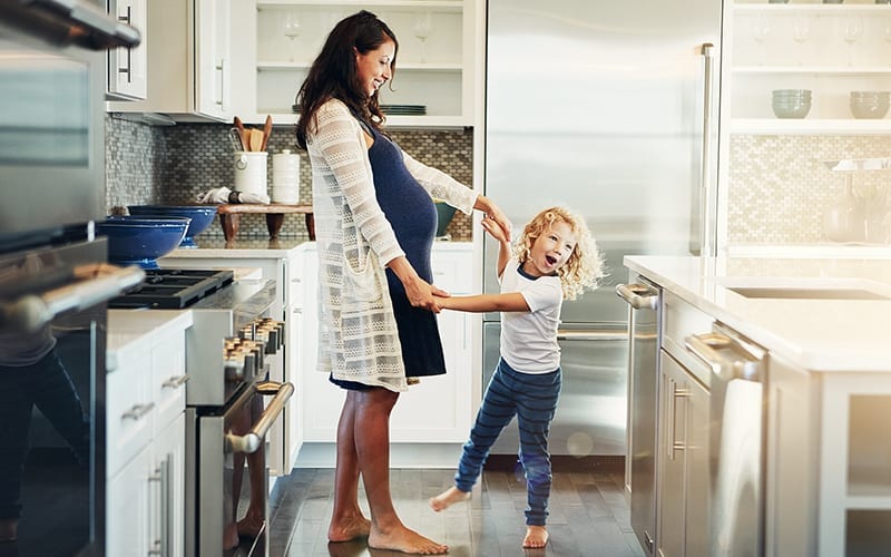 pregnant mom dancing with daughter in kitchen