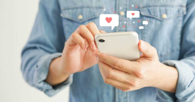 Close up young man holding smartphone to chat message with online people in dating website application