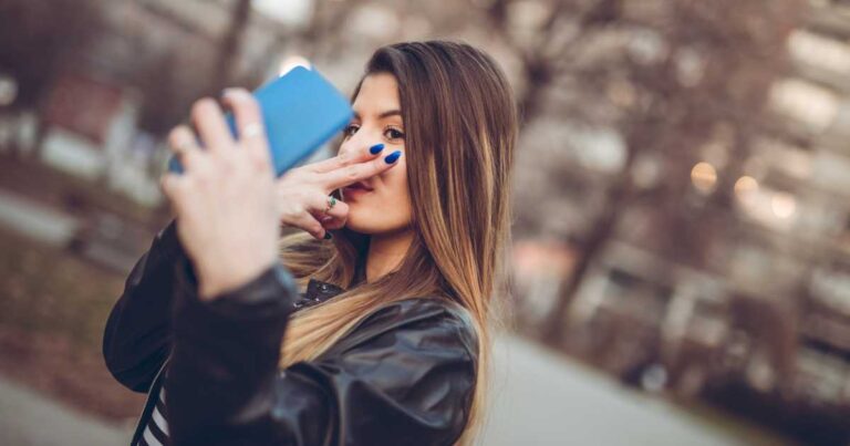 Young Caucasian pretty woman making selfies downtown.