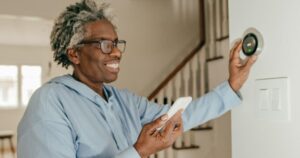woman-connecting-smart-phone-to-thermostat