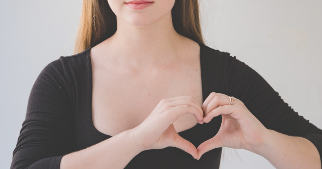 Woman making a heart shape with her hands over her chest